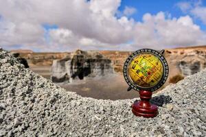a globe on top of a rock in a desert photo