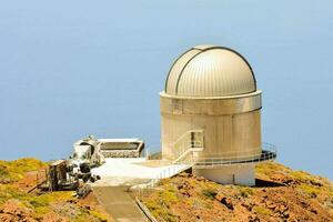 a telescope on top of a mountain with a blue sky photo