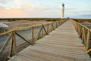 a wooden walkway leads to a lighthouse in the middle of the desert photo