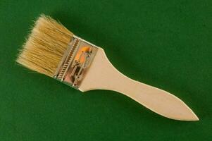 a brush with a wooden handle on a green surface photo