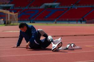 discapacitado atlético hombre extensión y calentamiento arriba antes de corriendo en estadio pista foto