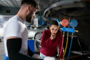 Car mechanic working in an auto repair shop explain to customer after inspecting the operation of the car's air conditioner and refrigerant photo