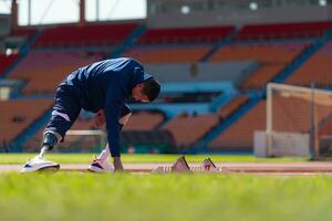 discapacitado atlético hombre extensión y calentamiento arriba antes de corriendo en estadio pista foto