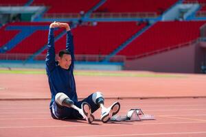 Disabled athletic man stretching and warming up before running on stadium track photo