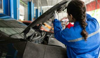 Car mechanic working in an auto repair shop, inspecting the operation of the car's air conditioner and refrigerant, Focus on woman photo