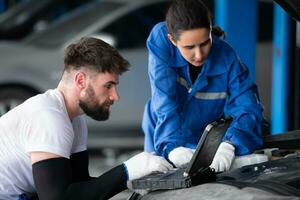 Professional auto mechanic man and woman working together in auto repair shop. photo