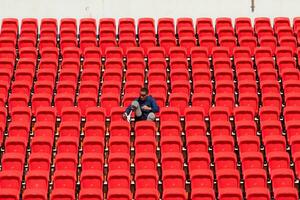 discapacitado Atletas en un azul camisa sentado en el rojo asientos a el estadio, preparar para corriendo capacitación. foto