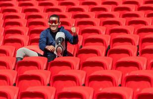 Disabled athletes in a blue shirt sitting on the red seats at the stadium, Prepare for running training. photo