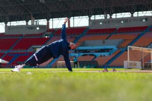 discapacitado atlético hombre extensión y calentamiento arriba antes de corriendo en estadio pista foto