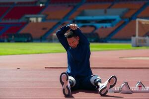 discapacitado atlético hombre extensión y calentamiento arriba antes de corriendo en estadio pista foto