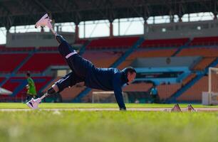 Disabled athletic man stretching and warming up before running on stadium track photo