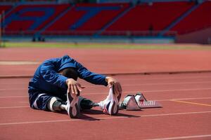 discapacitado atlético hombre extensión y calentamiento arriba antes de corriendo en estadio pista foto