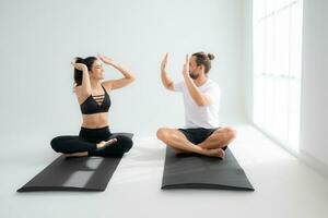 Young couple practicing yoga in a white room of studio. photo