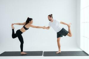 Young couple practicing yoga in a white room of studio. photo