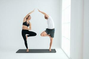 joven Pareja practicando yoga en un blanco habitación de estudio. foto