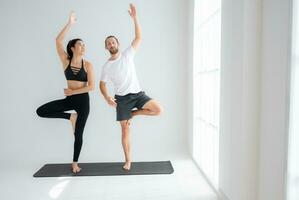 Young couple practicing yoga in a white room of studio. photo
