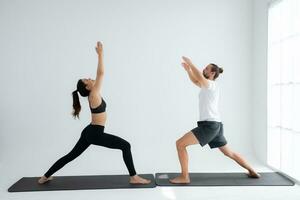 Young couple practicing yoga in a white room of studio. photo