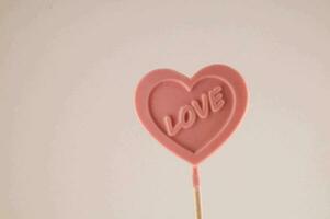 un rosado corazón conformado pirulí con el palabra amor escrito en eso foto