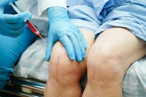 Asian doctor inject Hyaluronic acid platelet rich plasma into the knee of senior woman to walk without pain. photo