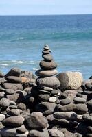 a stack of rocks on the beach near the ocean photo