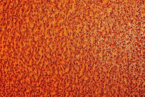 an orange metal surface with a few small spots photo