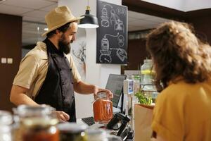 Zero waste shop entrepreneur owner selling vegan products to environmentally conscious client. Woman purchasing eco bio food in low carbon footprint local neighborhood store photo