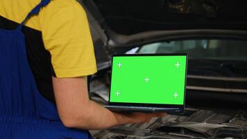 Certified mechanic using mockup laptop in car service to order new parts for damaged vehicle. Close up shot of specialist using device with isolated screen to look online for replacing components photo