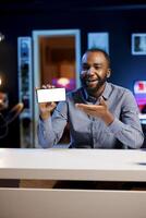 Man holding isolated screen smartphone in hand, using it as empty copy space to showcase his online streaming channel logo. Content creator does introductory video using mockup mobile phone photo