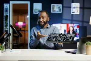 Internet show host being sponsored by partnering brand to do DJ controller unboxing content. Disc jockey does influencer marketing, doing turntables musical equipment product placement photo