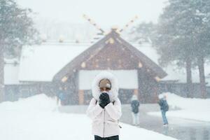 Woman tourist Visiting in Sapporo, Traveler in Sweater looking Hokkaido Shrine with Snow in winter season. landmark and popular for attractions in Hokkaido, Japan. Travel and Vacation concept photo