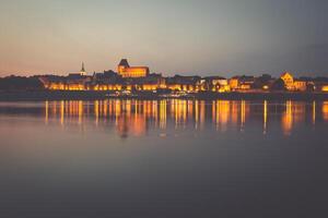 City of Torun in Poland, old town skyline by night from Vistula river photo