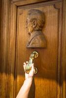 Closeup of knocking on door with door knocker. photo