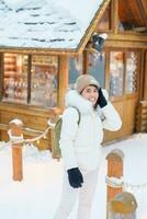 Woman tourist Visiting in Furano, Traveler in Sweater sightseeing Ningle Terrace Cottages with Snow in winter. landmark and popular for attractions in Hokkaido, Japan. Travel and Vacation concept photo