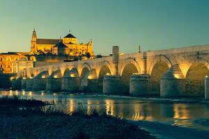 Night view of Mezquita-Catedral and Puente Romano - Mosque-Cathedral and the Roman Bridge in Cordoba, Andalusia, Spain photo