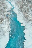 Shirahige Waterfall with Snow in winter, Biei river flow into Blue Pond. landmark and popular for attractions in Hokkaido, Japan. Travel and Vacation concept photo