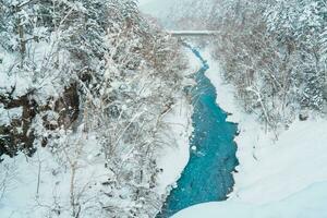 Shirahige Waterfall with Snow in winter, Biei river flow into Blue Pond. landmark and popular for attractions in Hokkaido, Japan. Travel and Vacation concept photo