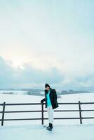 mujer turista visitando en Bien, viajero en suéter Turismo ver con nieve en invierno estación. punto de referencia y popular para atracciones en Hokkaidō, Japón. viaje y vacaciones concepto foto