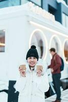 woman tourist holding hot Coffee or Tea paper cup with snow in winter season during travel in Niseko. landmark and popular for attractions in Hokkaido, Japan. Travel and Vacation concepts photo