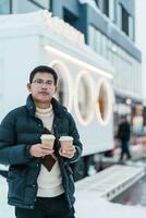 man tourist holding hot Coffee or Tea paper cup with snow in winter season during travel in Niseko. landmark and popular for attractions in Hokkaido, Japan. Travel and Vacation concepts photo