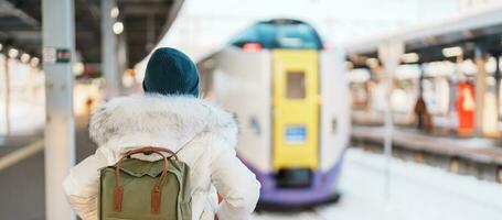 Woman tourist with bag in Train Station platform with Snow in winter. Hakodate, Hokkaido, Japan.Travel and Vacation concept photo