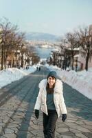 Woman tourist Visiting in Hakodate, Traveler in Sweater sightseeing Hachiman Zaka Slope with Snow in winter. landmark and popular for attractions in Hokkaido, Japan. Travel and Vacation concept photo