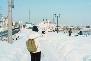 Woman tourist Visiting in Hakodate, Traveler in Sweater sightseeing Hakodate port near Red Brick Warehouse with Snow in winter. Hokkaido, Japan.Travel and Vacation concept photo