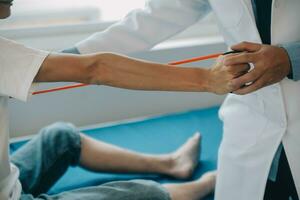 Doctor or physical therapist examines back pain and spinal area to give advice within the rehabilitation center. photo