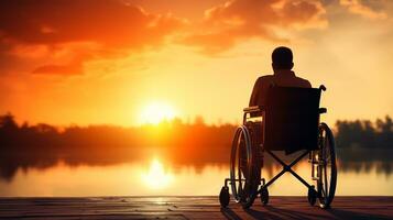 Silhouette of disabled man on wheelchair at the beach during sunset, Disable day photo