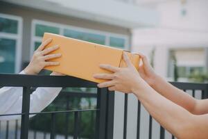 Asian Woman Receiving Product from delivery man at Home, Young Owner Woman Order Product from Smartphone Application, Woman with Online Business or SME Concept. photo