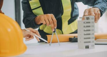 reunión de trabajo en equipo de ingenieros, trabajo de dibujo en la reunión de planos para el trabajo del proyecto con un socio en la construcción de modelos y herramientas de ingeniería en el concepto de sitio de trabajo, construcción y estructura. foto