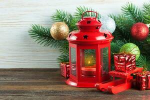 Lantern and Christmas tree over snow on wooden background photo