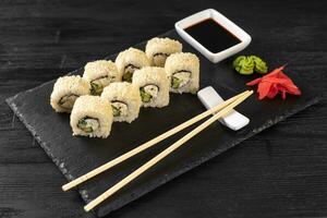 Sushi roll Philadelphia with salmon, sesame seeds, avocado, cream cheese on black slate background photo