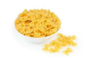 Raw pasta farfalle in bowl isolated on white background photo