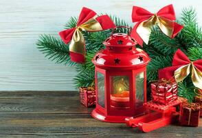 Lantern and Christmas tree over snow on wooden background photo